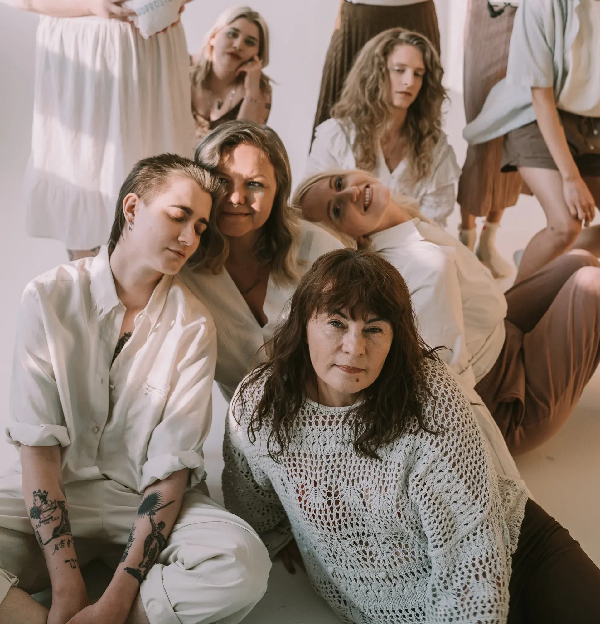 Liczny zespół aktywistek Aborcyjnego Dream Teamu siedzący gromadnie na podłodze. Osoby ubrane są w jasne ubrania i siedzą w zrelaksowanych pozycjach.